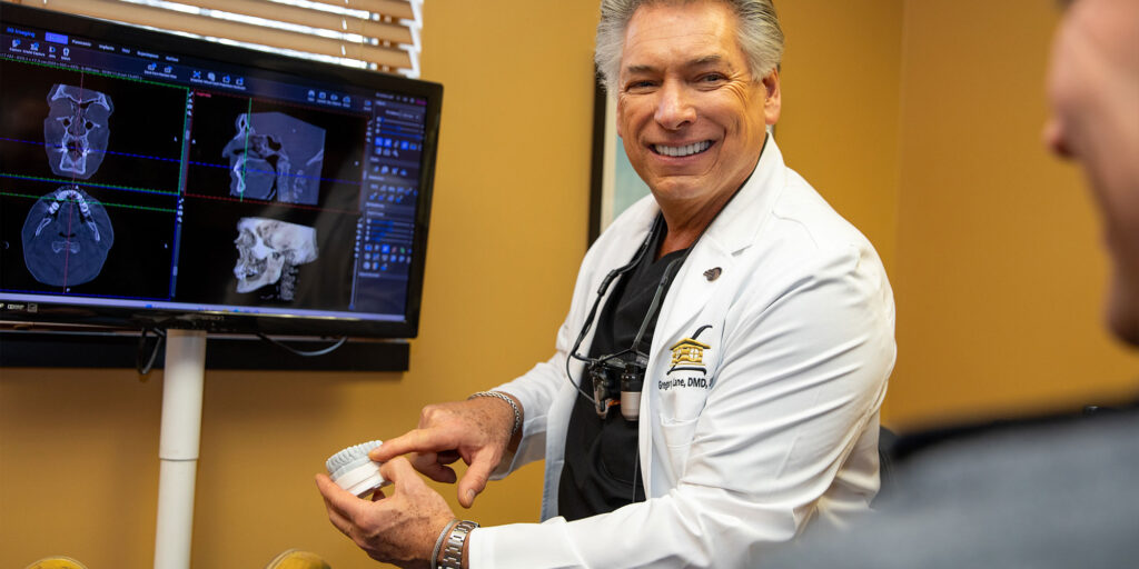 Doctor going over procedure with patient holding up a model of teeth