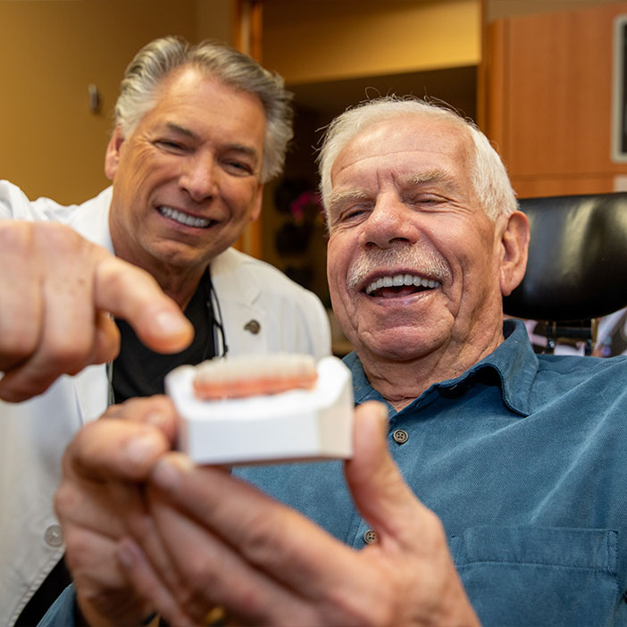 Patient holding a model of dental implants