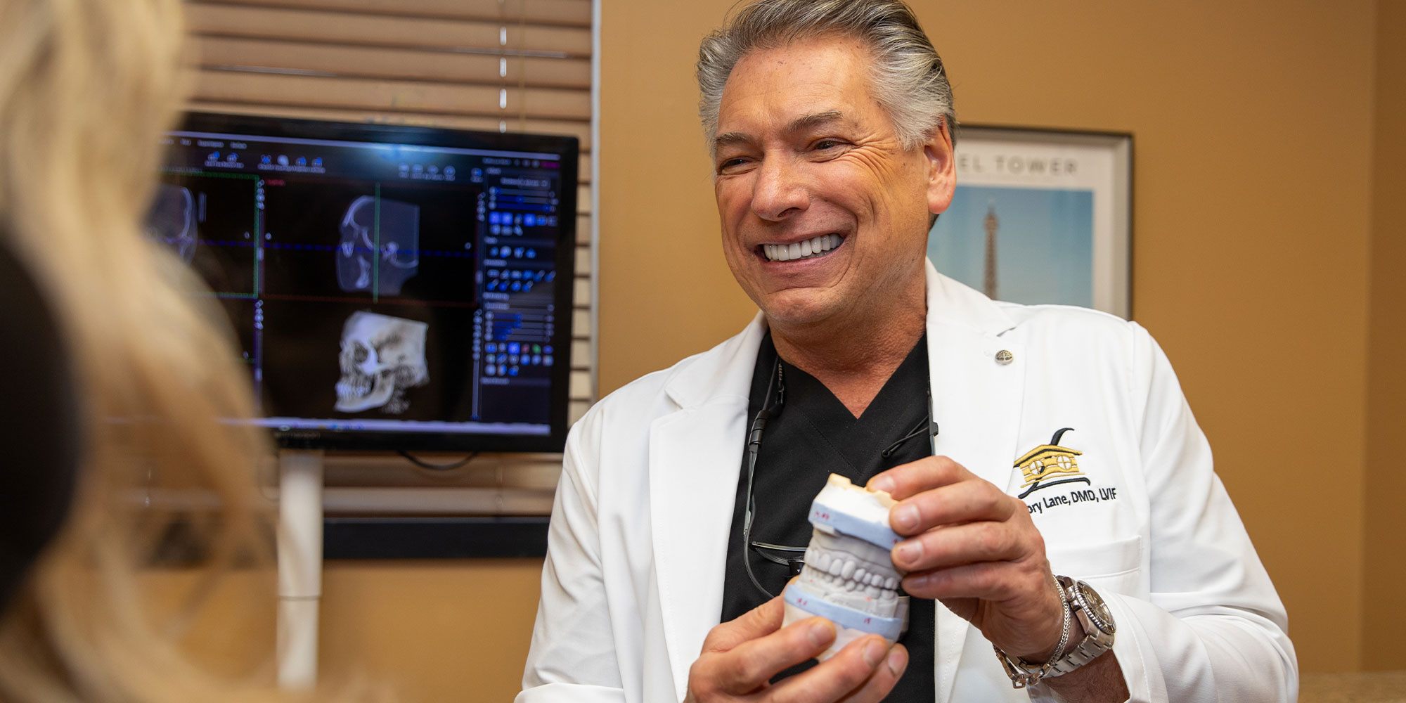 Doctor holding up a model of teeth to Patient