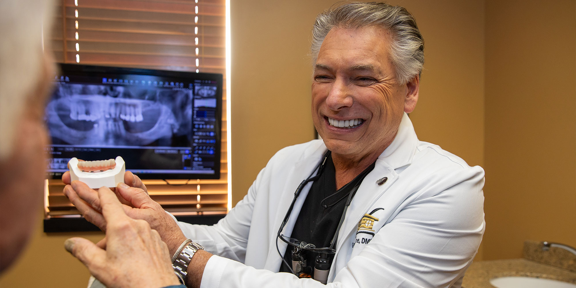Doctor holding up a model of a full arch Implant